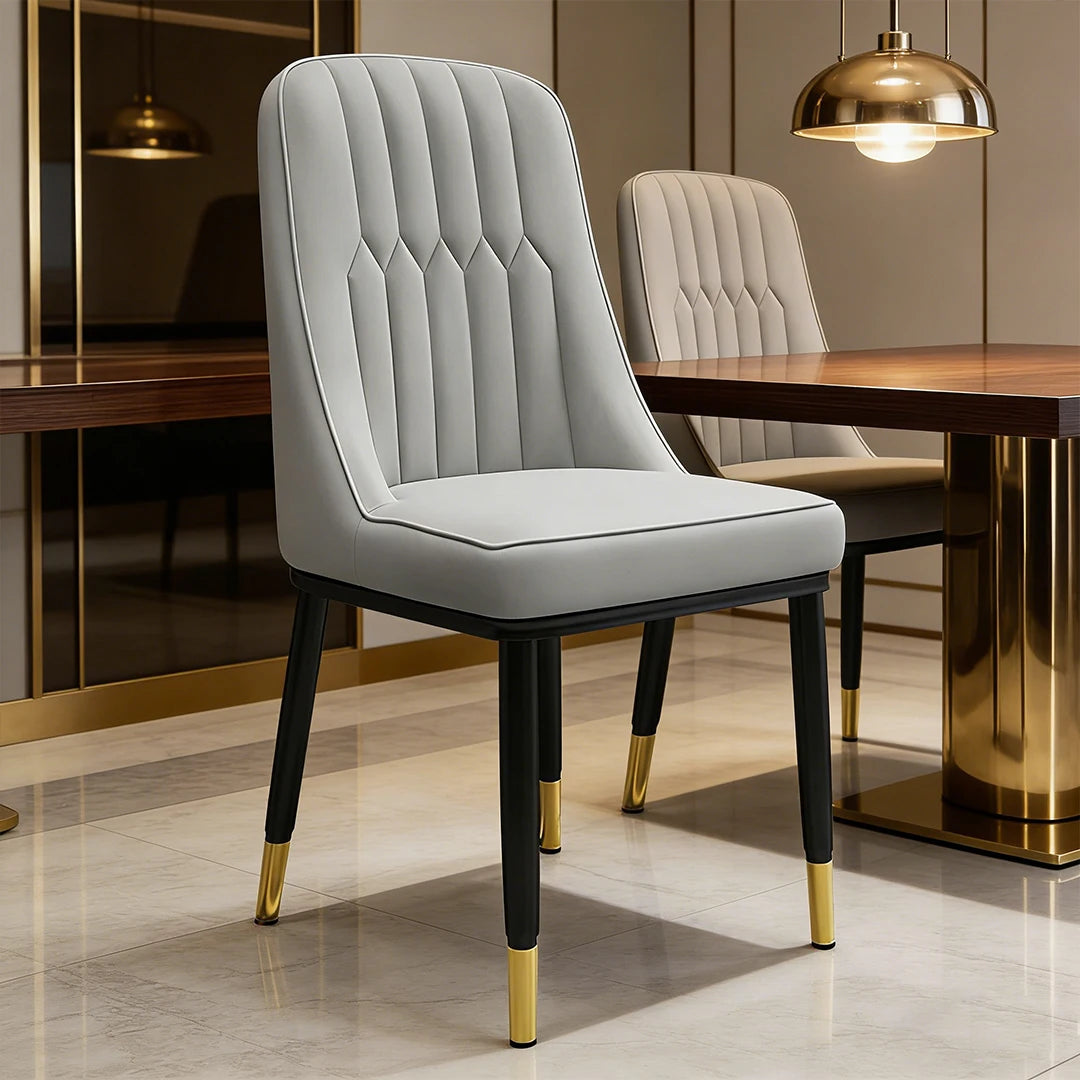 Light gray dining chair with tufted back, padded seat, black frame, gold tapered legs