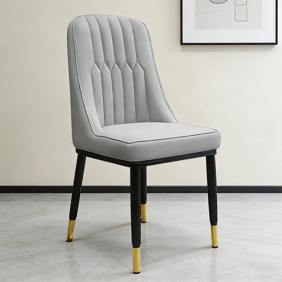 Light gray dining chair with padded seat and tufted back, black legs with gold tips