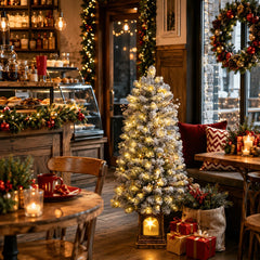 Snow-frosted pre-lit potted Christmas tree with warm white lights and full snowy branches