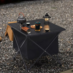 Black camping folding table with slatted top and storage bin, set with cookware