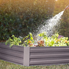 Outdoor raised bed planter with dark gray slats while watering plants.