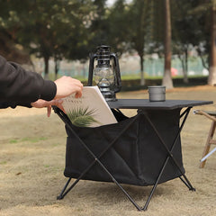 Black outdoor folding table with slatted top and storage bin, table packed with items