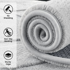 Light gray shag area rug rolled up, dense plush pile with thick textured edge