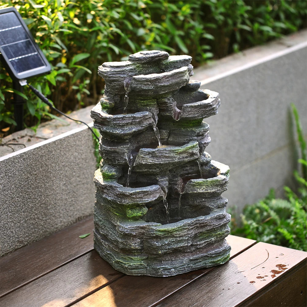 Grey faux rock garden water fountain sculpture on patio with stacked stone tiers