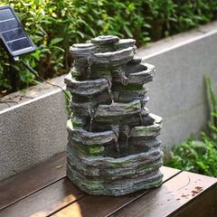 Grey faux rock garden water fountain sculpture on patio with stacked stone tiers