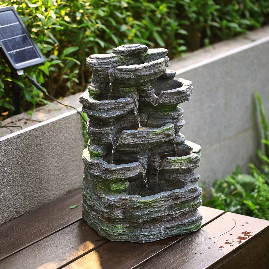Grey faux rock garden water fountain sculpture on patio with stacked stone tiers
