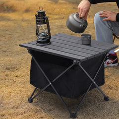 Black folding camping table with slatted top and storage bin, on metal X-legs