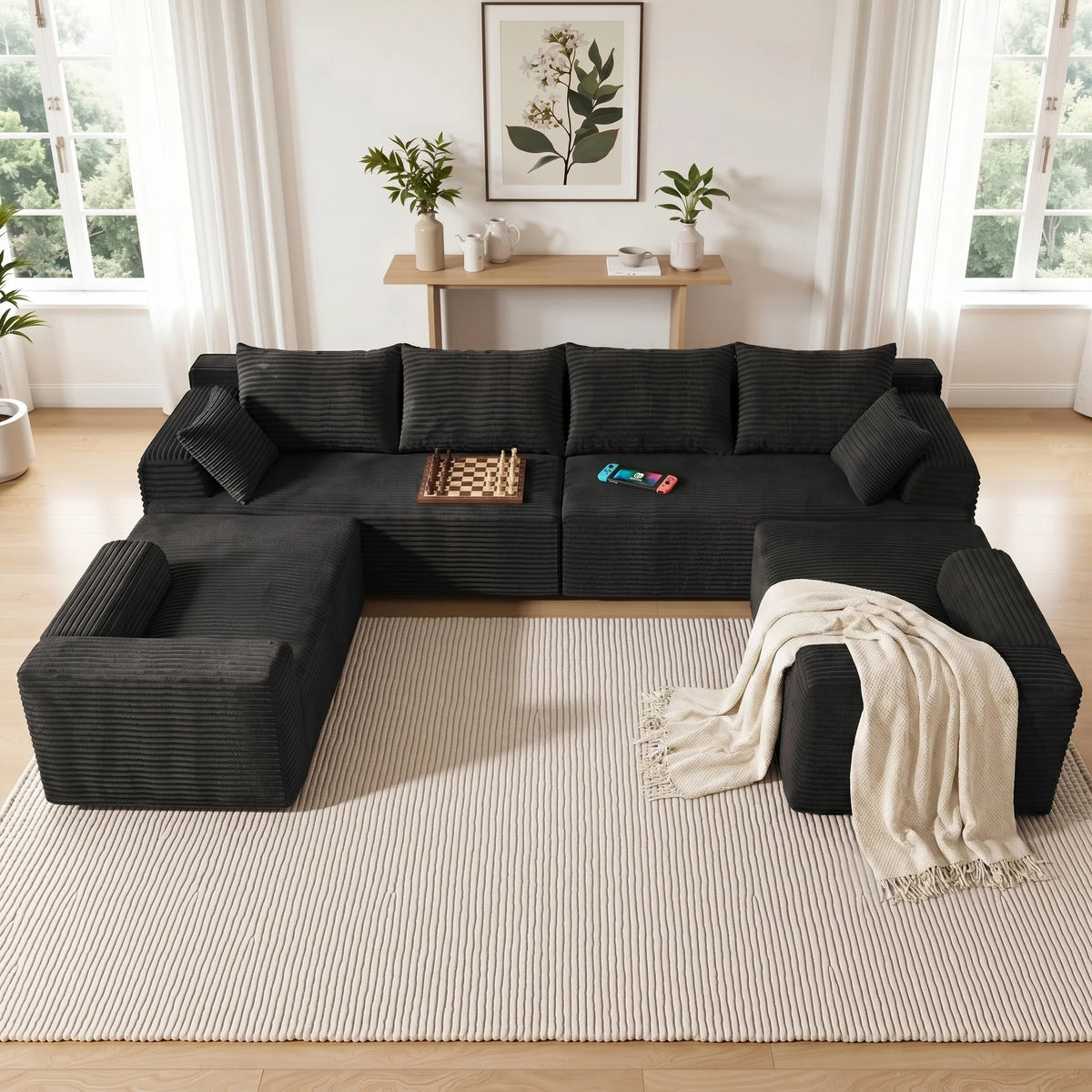 Black corner sectional sofa with deep seating, back pillows, and folded blanket