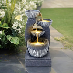 Solar outdoor fountain with tiered gray stone basins, lit water stream, and solar panel