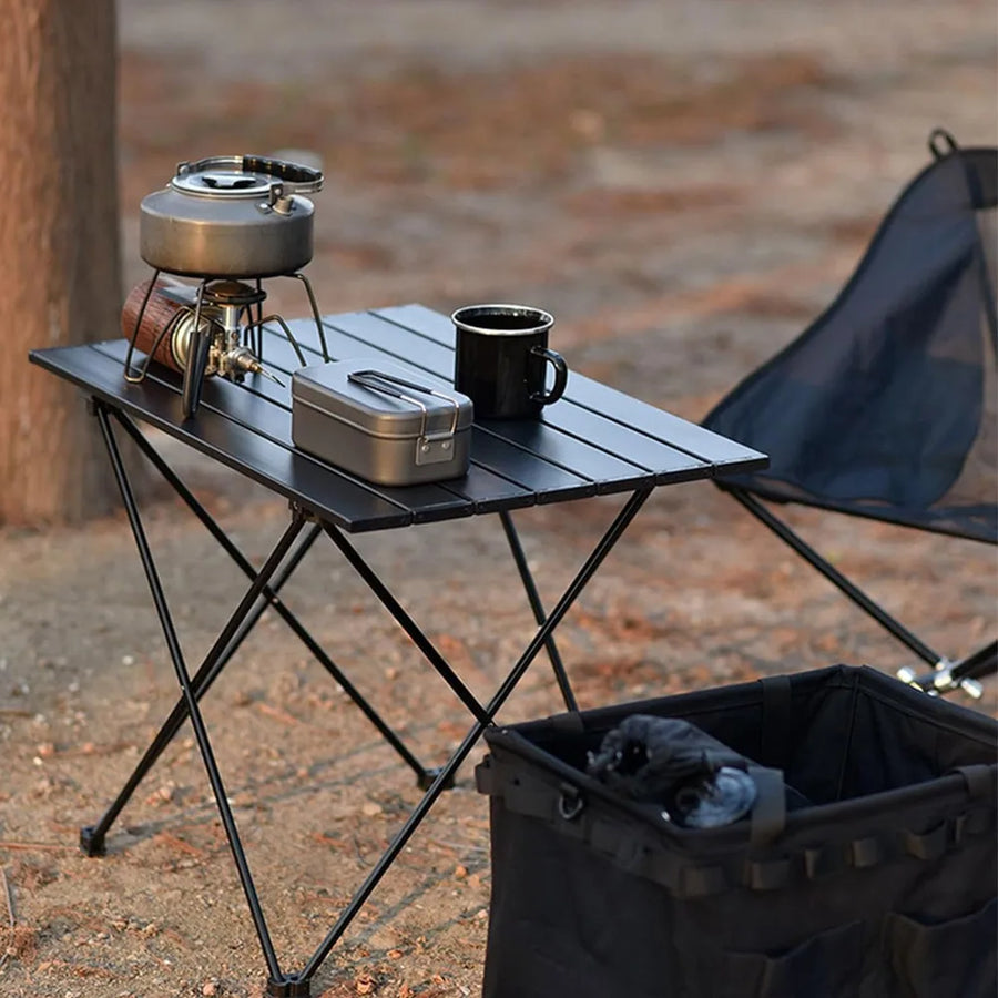 Black portable folding table with slatted surface and storage pouch, with side lantern