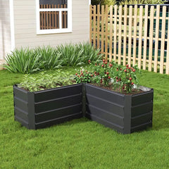 Charcoal black L-shaped metal raised garden bed with raised tiers, filled with plants