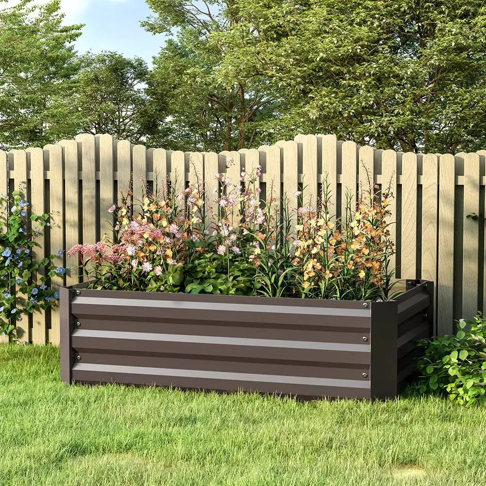 Outdoor raised bed planter with dark gray slatted sides, filled with flowers in garden.