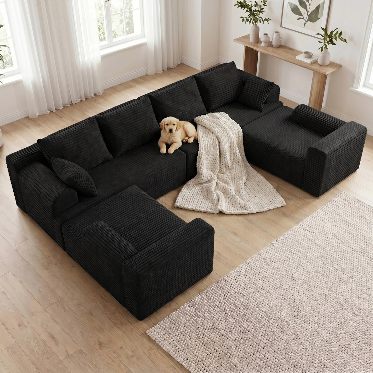 Black modular corner sofa with deep cushions and textured fabric throw on seat