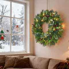 Evergreen Christmas wreath with red berries and pinecones, lit with warm bulbs