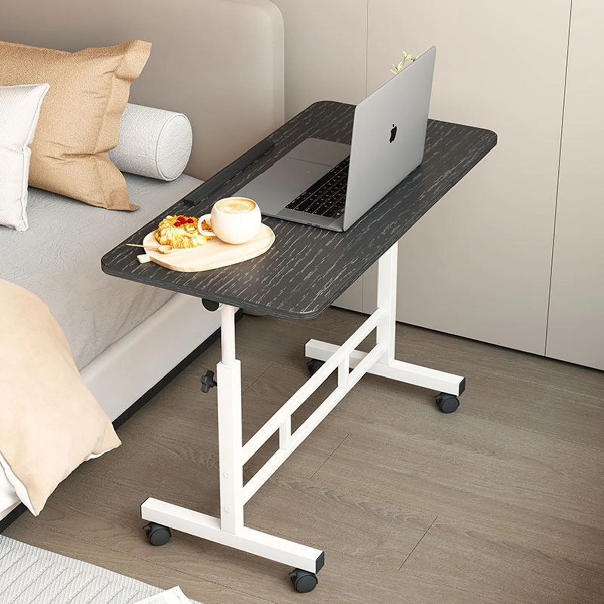 Mobile standing desk with black tabletop, white frame, and caster wheels