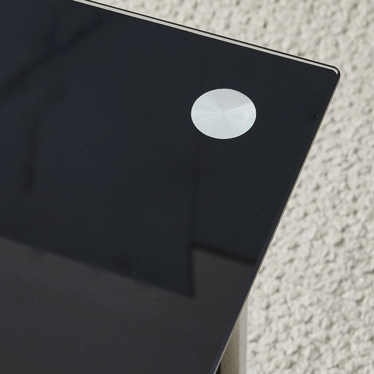Black glass tabletop corner detail with circular edge cap