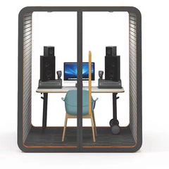 Sound recording pod with glass walls, desk setup, speakers, and chair inside