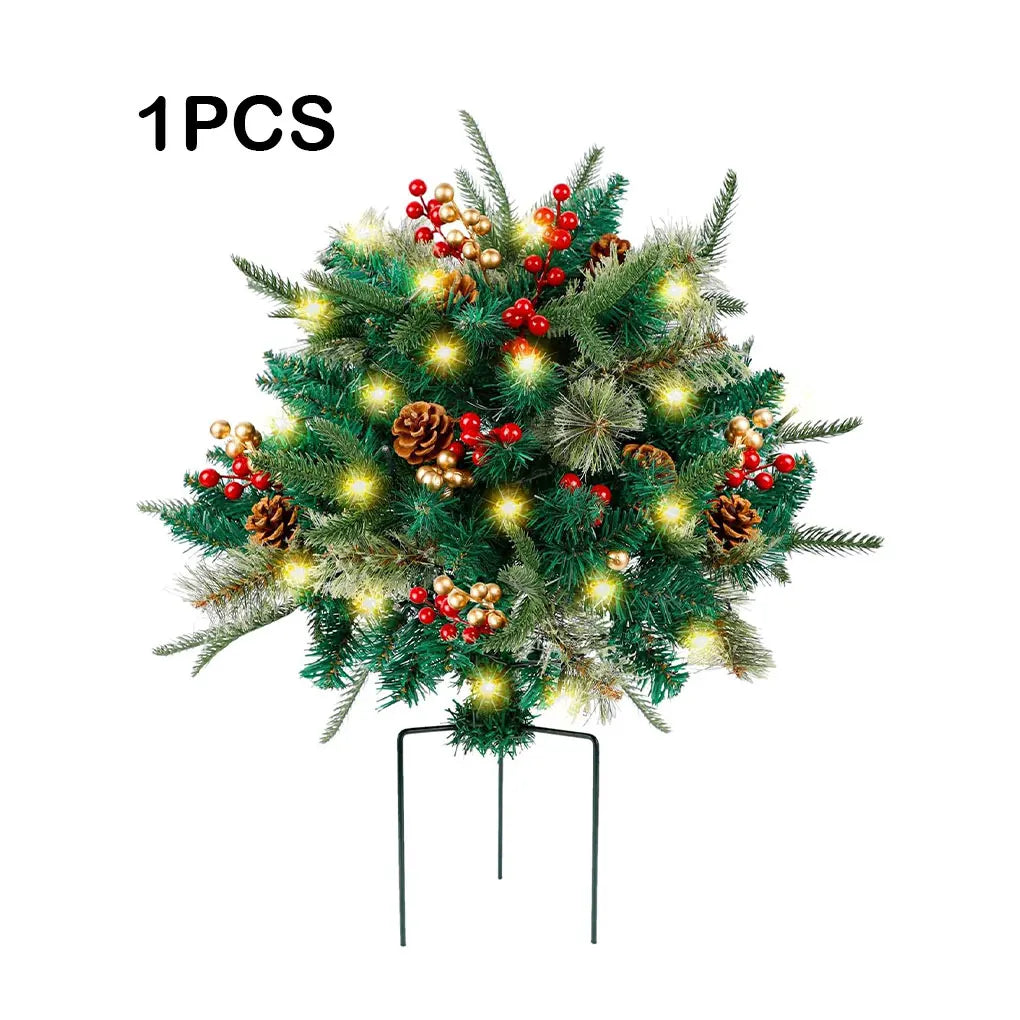 Green Christmas tree with warm white lights, red baubles, and pine cones on stake stand