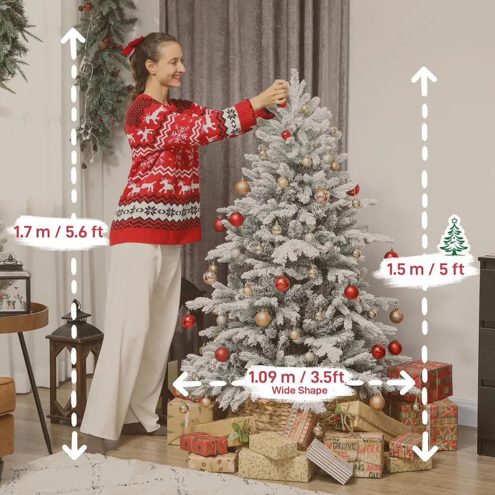 Snow-flocked artificial Christmas tree with ornaments while someone positions the branches
