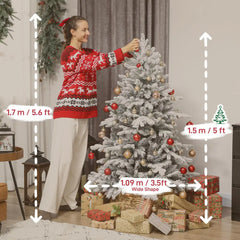Snow-flocked artificial Christmas tree with ornaments while someone positions the branches