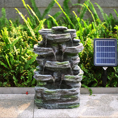 Grey faux rock garden fountain with lights and solar panel stake beside greenery