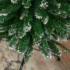Snow-dipped artificial Christmas tree branches with white flocking on green needles