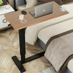 Adjustable bedside laptop desk with wood-look top, black base, and tabletop accessories