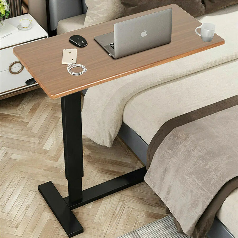 Adjustable bedside laptop desk with wood-look top, black base, and tabletop accessories