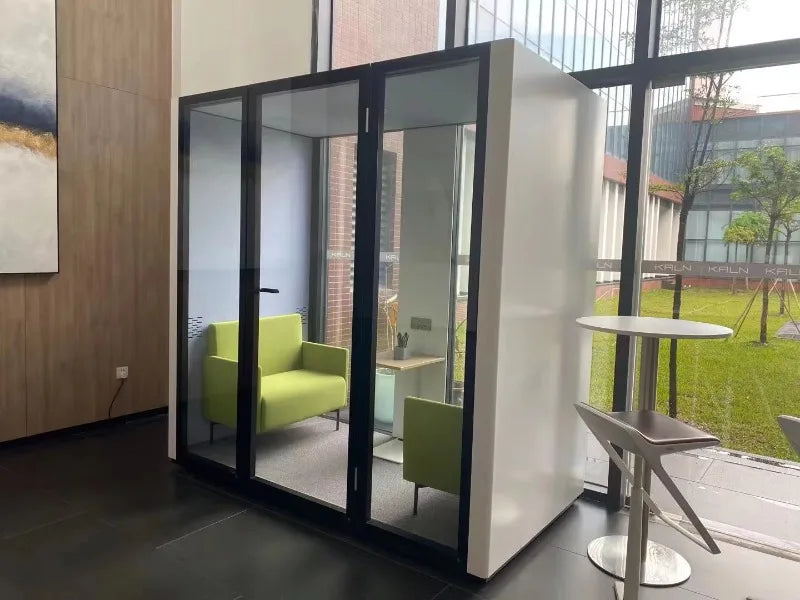 Portable quiet work pod with black-framed glass doors, outdoor patio view with chairs