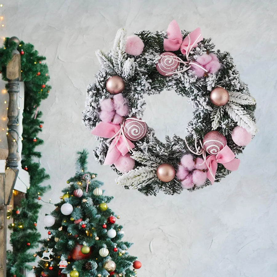 Decorative frosted wreath with pink flower accents, pom poms, and rose-gold baubles.